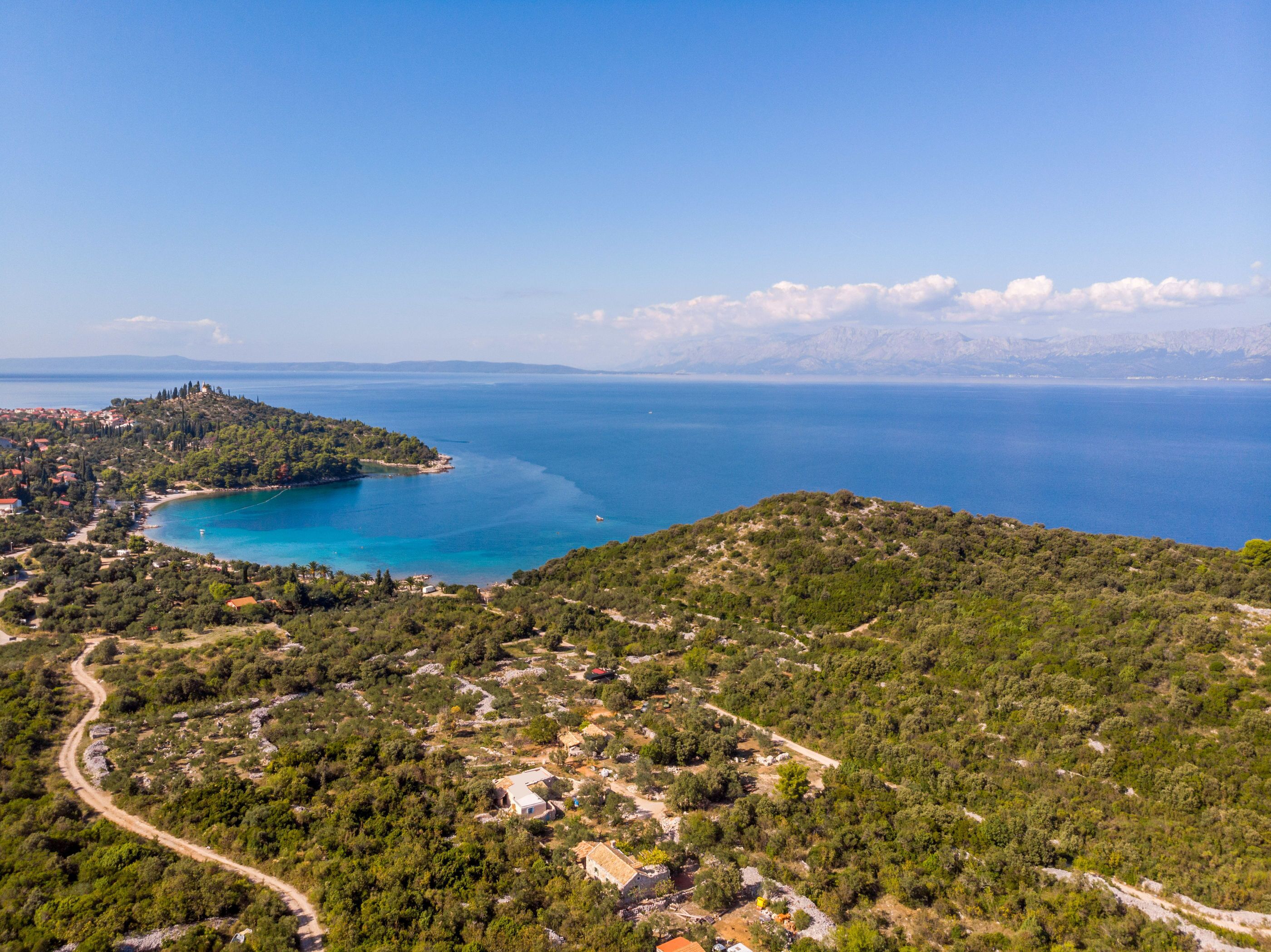 Un paisaje costero con vista despejada al mar, una carretera serpenteante y edificios dispersos.