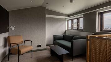 A modern room with a grey sofa, a brown chair, a small table, and a window with a view of buildings.