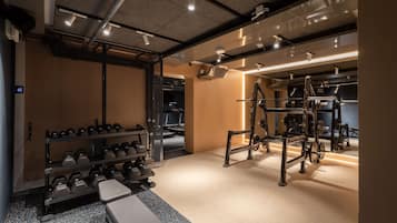 Ein Fitnessraum mit Gewichtsbänken, Hantelgestellen und Trainingsgeräten.