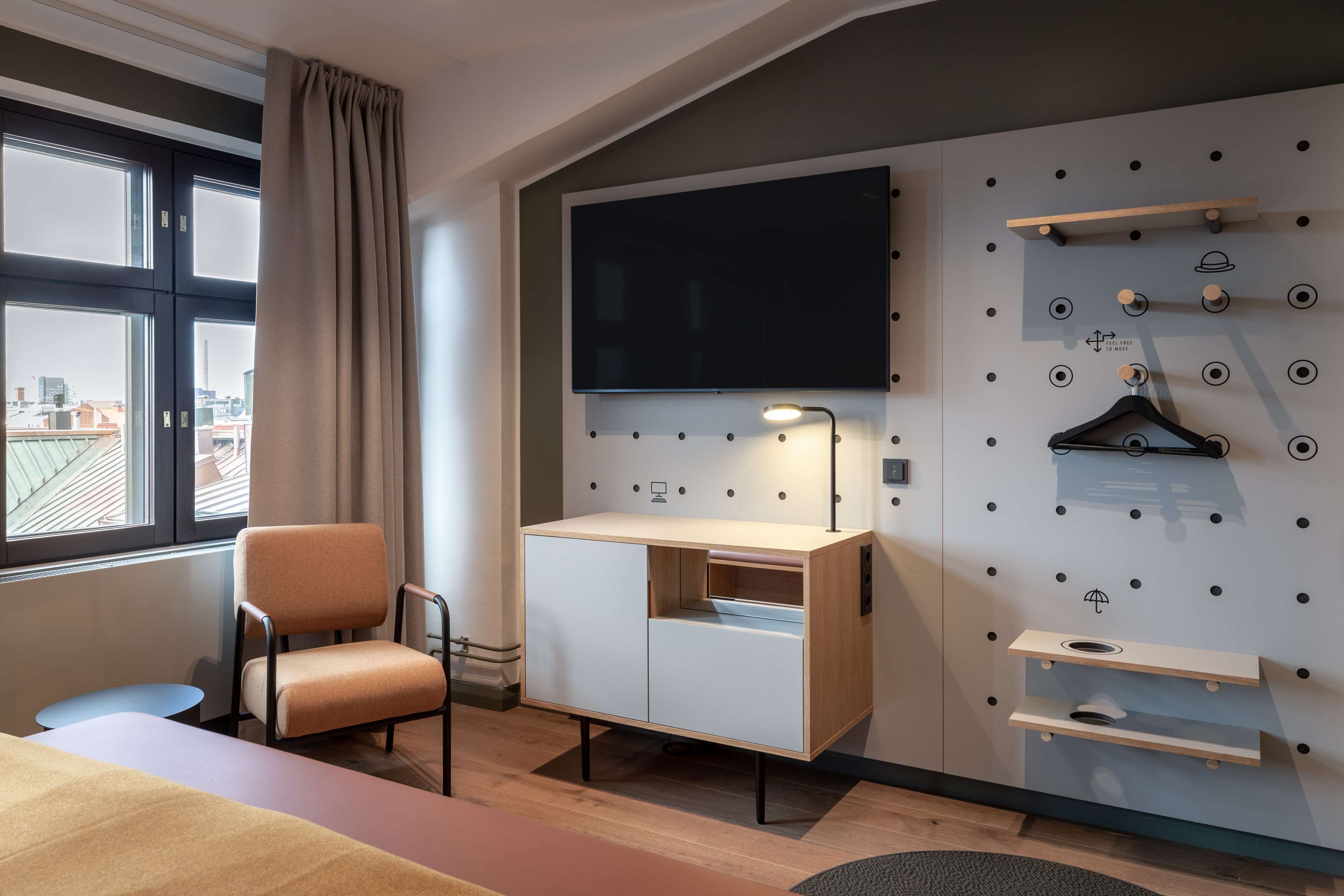 Habitación de hotel con escritorio, silla, televisión y almacenamiento en la pared.