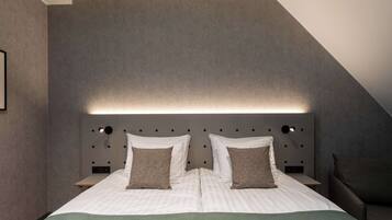 Een moderne hotelkamer met een groot bed, een hoofdeinde met geïntegreerde verlichting, een nachtkastje en een stoel.