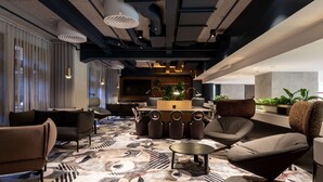 Un espacio lounge moderno con alfombra estampada, muebles contemporáneos y una barra central.
