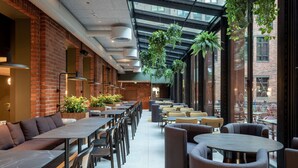 Un comedor moderno con paredes de ladrillo, ventanas amplias y plantas colgantes.