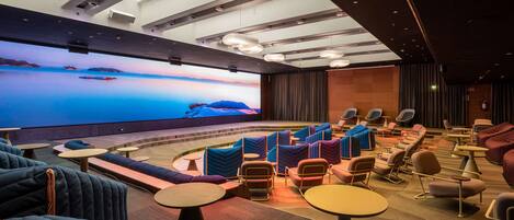 Un cine moderno con una pantalla grande, asientos cómodos y un interior bien iluminado.