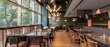 A restaurant with high ceilings, large windows, and a variety of seating arrangements including tables and booths.