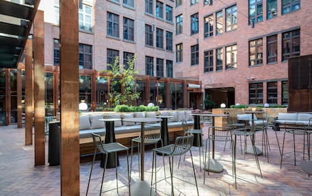 An outdoor seating area with tables and chairs, a wooden bench, and a small garden.