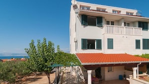 A two-story building with a balcony, a covered patio, and a view of the sea. - Apartment Irena (Supetar)