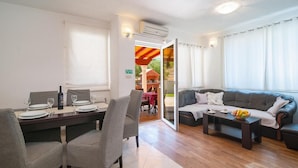 A dining area with a table set for two, a sofa, and a view of the outdoor patio. - Apartment Irena (Supetar)