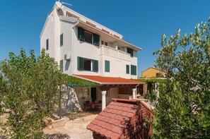 A two-story house with a balcony, a covered patio, and a garden area. - Apartment Irena (Supetar)