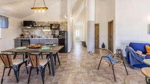 Une cuisine spacieuse avec un coin repas, comprenant une grande table, des chaises et un luminaire suspendu.