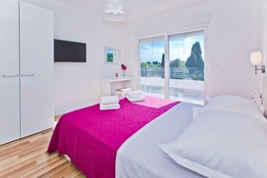 Relax in a spacious room with a large bed, flat-screen TV, and sliding glass door leading to a balcony.