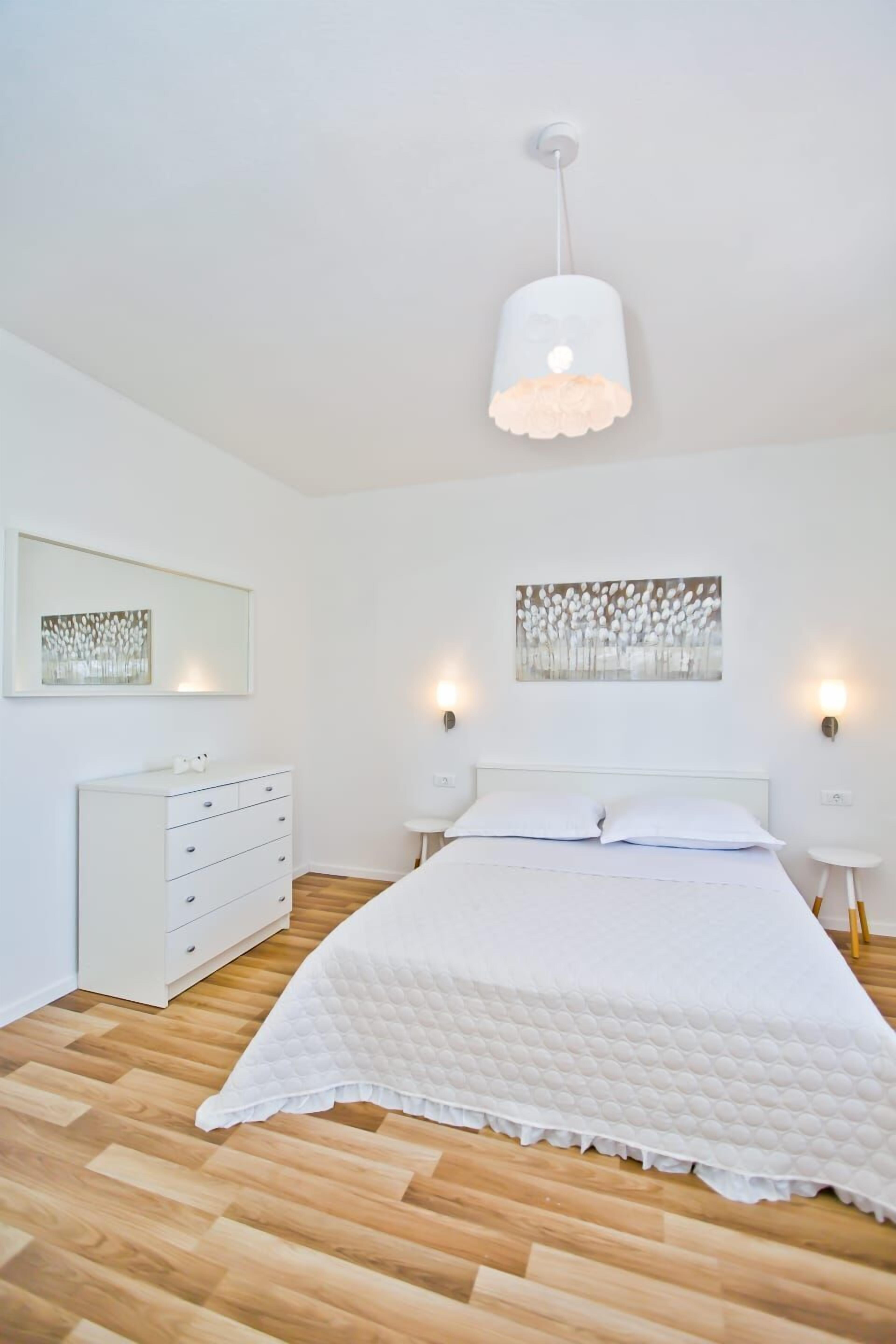 A bedroom with a bed, a dresser, and wall art.