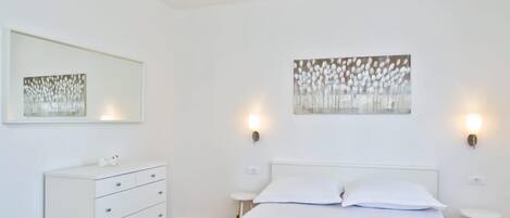 A bedroom with a bed, a dresser, and wall art.