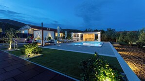 Une maison moderne dotée d’une piscine, d’un espace salon extérieur et d’un jardin bien entretenu.