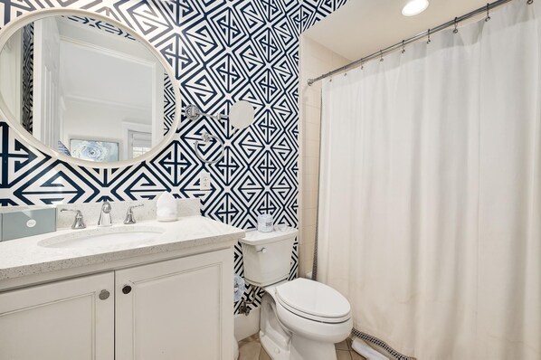 A bathroom with a white sink, a toilet, and a shower curtain.