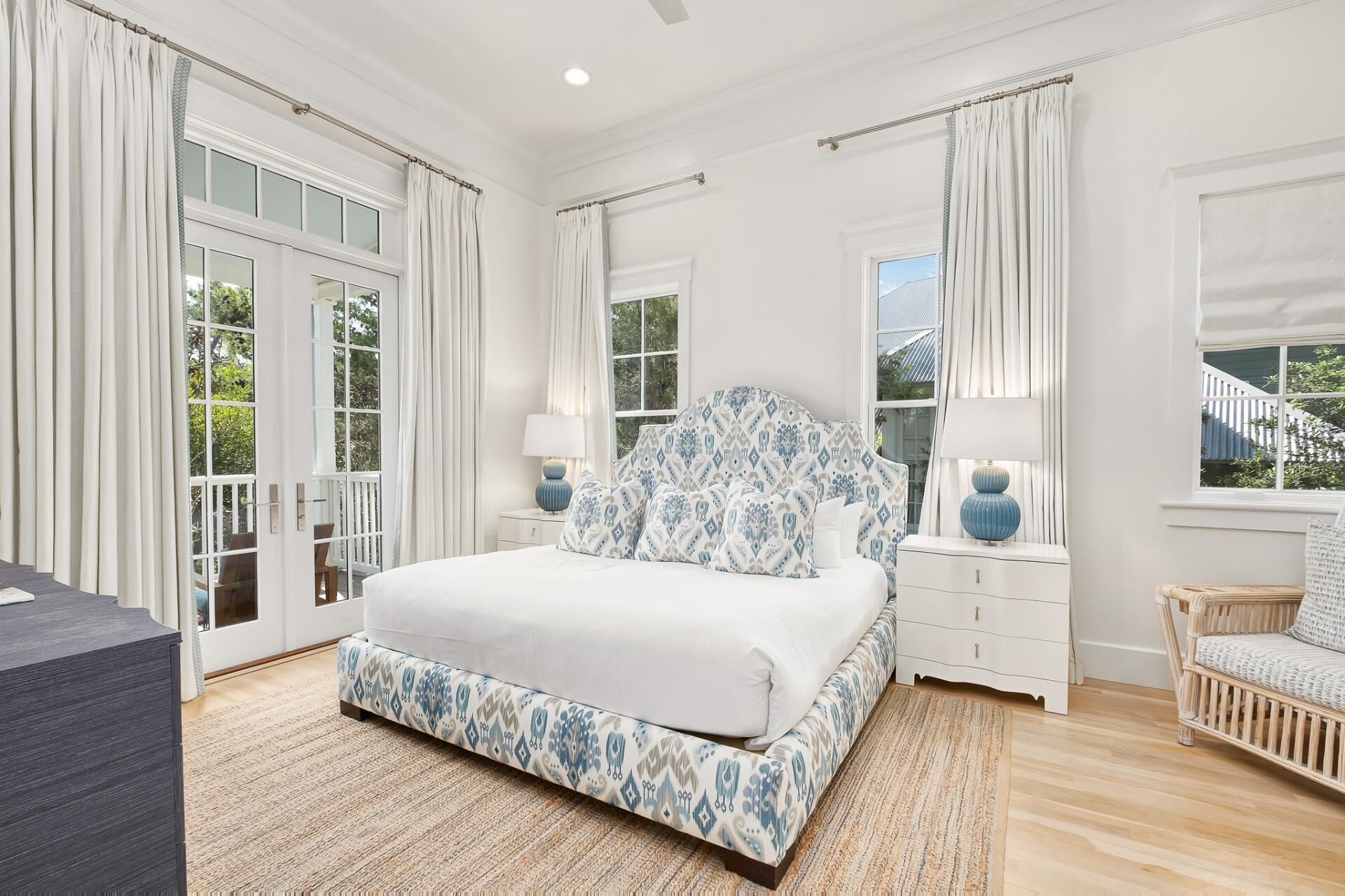 Un dormitorio con una cama grande, una mesita de noche, una silla y una ventana con cortinas.