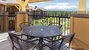 A covered outdoor patio with a round table and chairs, overlooking a forested area and distant mountains. - Worldmark Resort,3B2Bath!! Next to park! Sleeps 8 Very NICE (West Yellowstone)