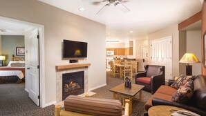 A hotel room with a fireplace, a television, a dining area, and a living room with a sofa and armchair. - Worldmark Resort,3B2Bath!! Next to park! Sleeps 8 Very NICE (West Yellowstone)
