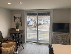 Relax in a serene space with a sliding glass door leading to a covered outdoor area, a flat-screen TV, and a cozy seating arrangement.