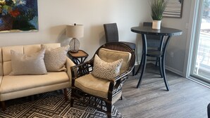 Un salon avec un canapé, deux fauteuils, une petite table avec une lampe, une plante en pot et un tableau accroché au mur.