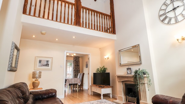 A spacious living room with leather sofas, a fireplace, a television, and a dining area with a table and chairs. - 45 Benton (Chester)