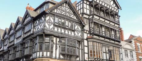 A historic building with Tudor-style architecture, featuring a prominent corner with a black and white timber frame, large windows, and a sign for Sole Trader.