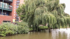 A river with weeping willow trees and a multi-story building with balconies. - 45 Benton (Chester)