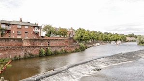 A river with a weir, brick buildings, and trees along the riverbank. - 45 Benton (Chester)