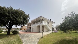 Una casa de dos pisos con fachada de piedra, un balcón y un camino de piedra que lleva a la entrada.