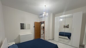 Un dormitorio con cama, armario, espejo y puerta que da a otra habitación.