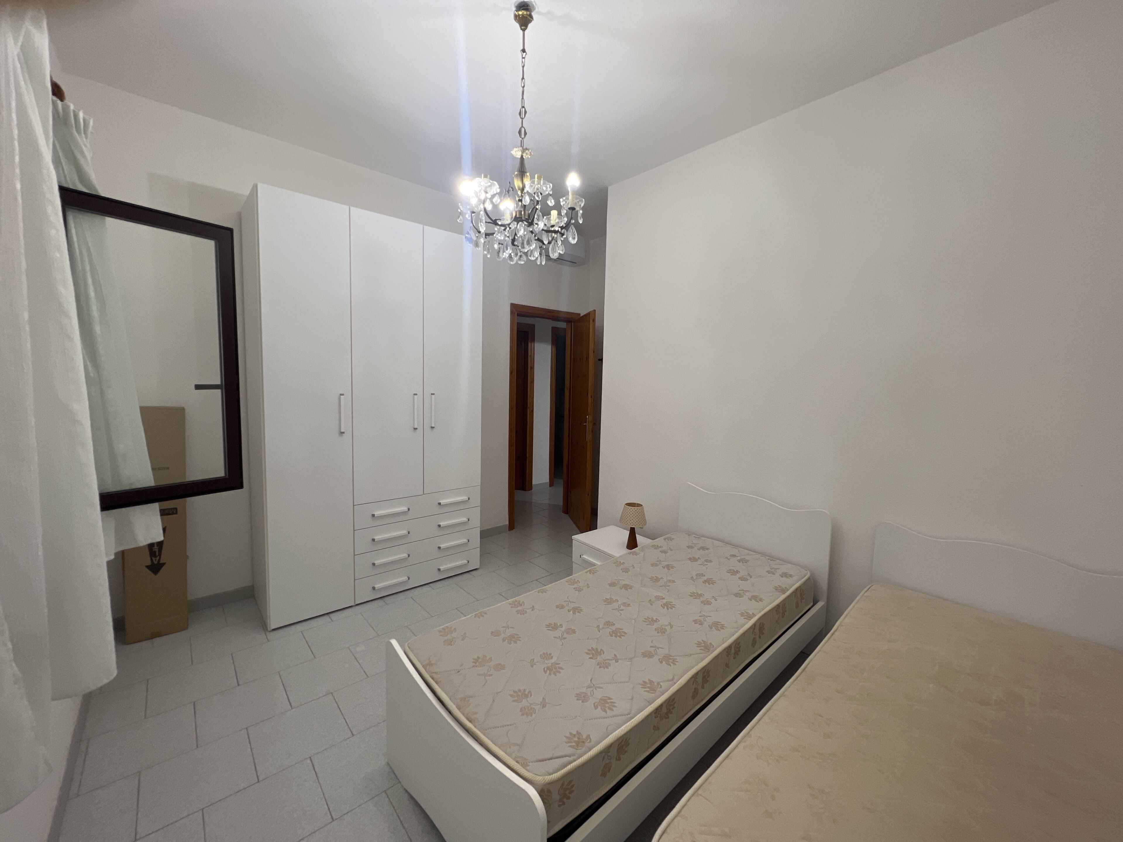 Een slaapkamer met een bed, een kledingkast, een spiegel en een kroonluchter.
