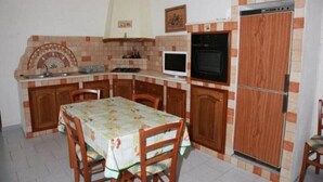 Una cocina compacta con mesa, sillas, microondas, estufa y refrigerador.