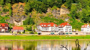 Uma cidade à beira de um lago, com edifícios tradicionais, um rio e uma encosta rochosa.