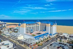 Um hotel grande com várias torres de telhado azul, vista para a praia e estacionamento.