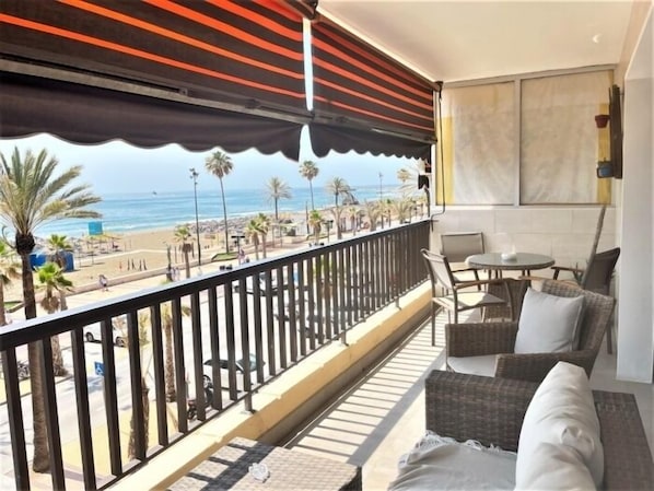 Ein Balkon mit Blick auf den Strand, Korbmöbel und einem Geländer.