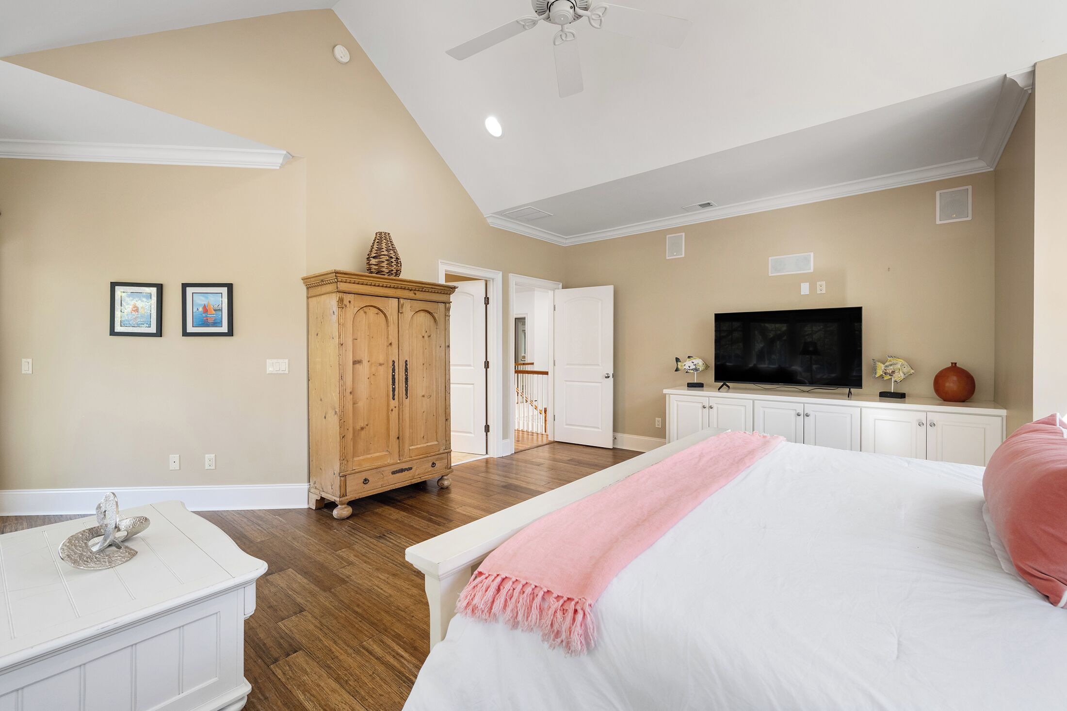 Un dormitorio con una cama, un armario de madera, un televisor y un ventilador de techo.