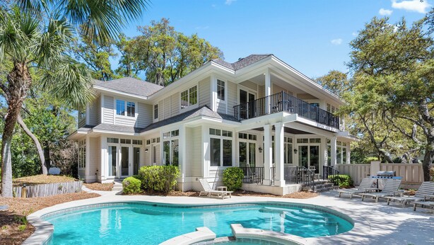 A two-story house with a swimming pool, large windows, and a balcony. - Pristine 2nd row home in Sea Pines w/ great outdoor space, private pool & spa (Hilton Head Island)