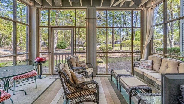 A covered patio with wicker furniture, a table, and ceiling fans.