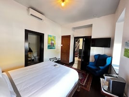 Een hotelkamer met een bed, een bureau, een stoel, een televisie en een airconditioner.