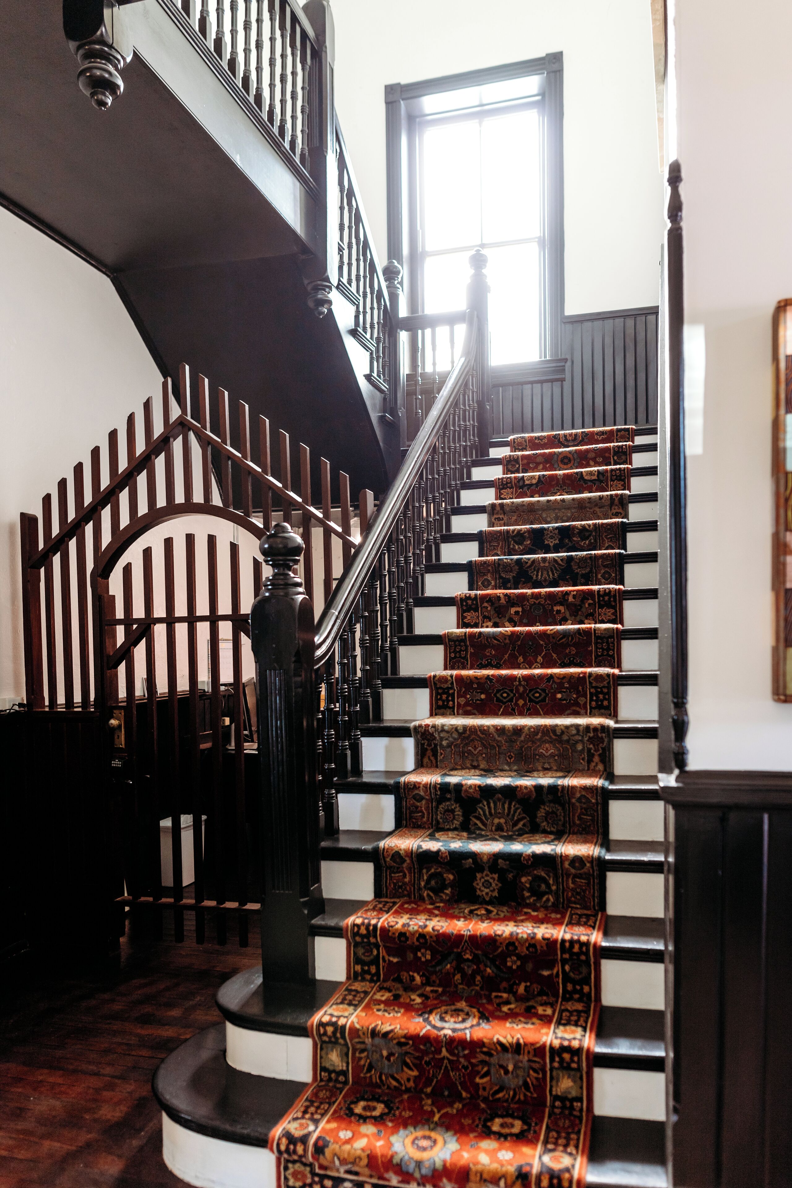 Un escalier orné de rampes décoratives et recouvert d’une moquette à motifs.
