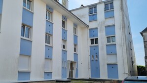 Ein mehrstöckiges Gebäude mit einer blau-weißen Fassade, das mehrere Fenster und Balkone aufweist.