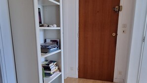 Ein Flur mit einer Holztür, einem weißen Bücherregal und einer Deckenleuchte.