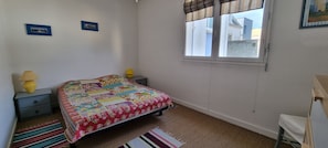 A bedroom with a bed, two bedside tables with lamps, a window, and a small easel. - Beautiful apartment in the center of Concarneau with private parking (Concarneau)