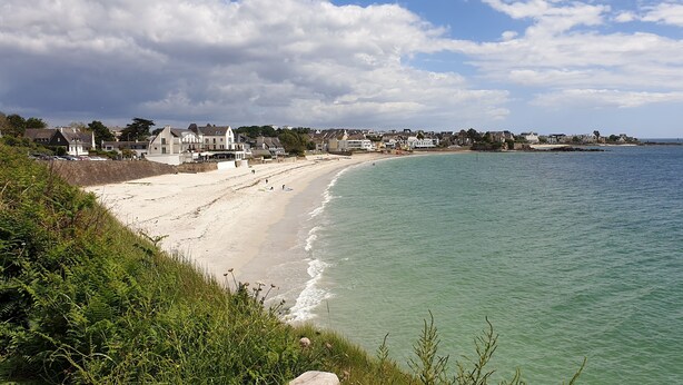 Eine Küstenstadt mit Sandstrand, Häusern entlang der Uferlinie und Blick auf das Meer.