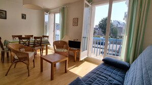 Ein Wohnzimmer mit einer Couch, einem Esstisch, Stühlen und einem Fernseher.