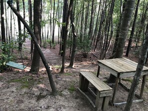 Un área boscosa con un banco de madera y una mesa de picnic.