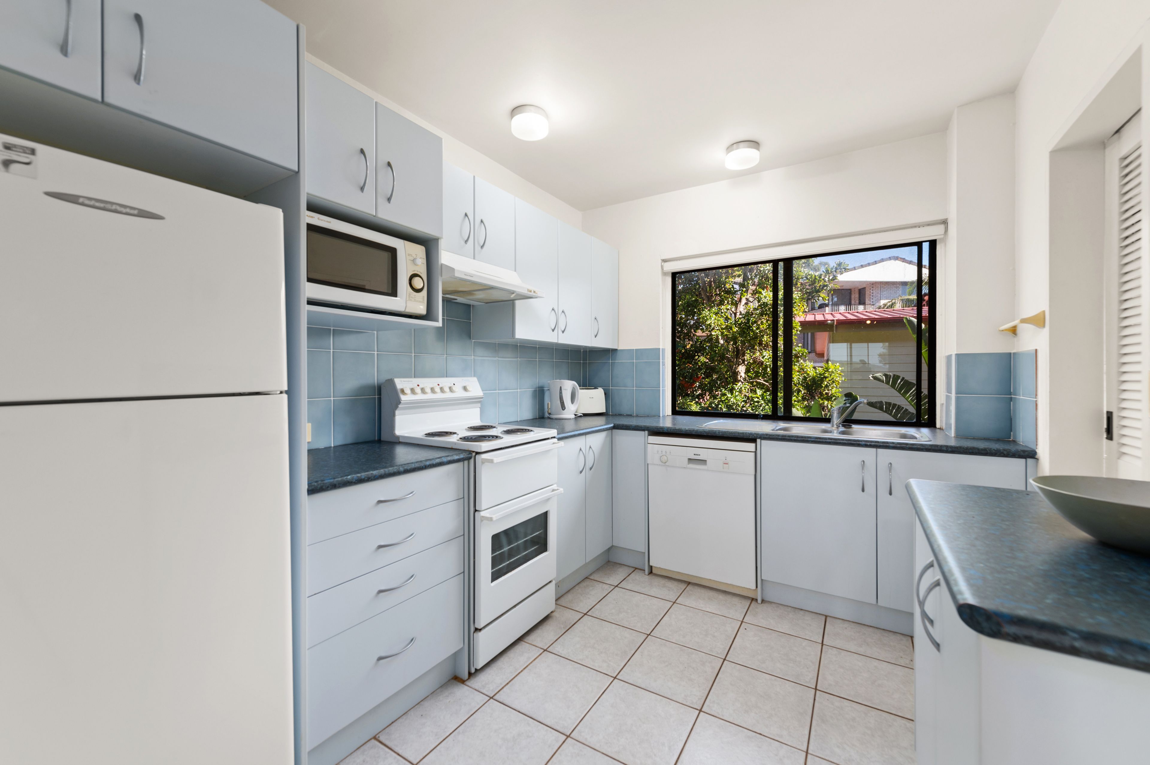 A modern kitchen with white cabinets, a built-in microwave, a stove, and a dishwasher.