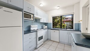 A modern kitchen with white cabinets, a microwave, stove, and dishwasher.
