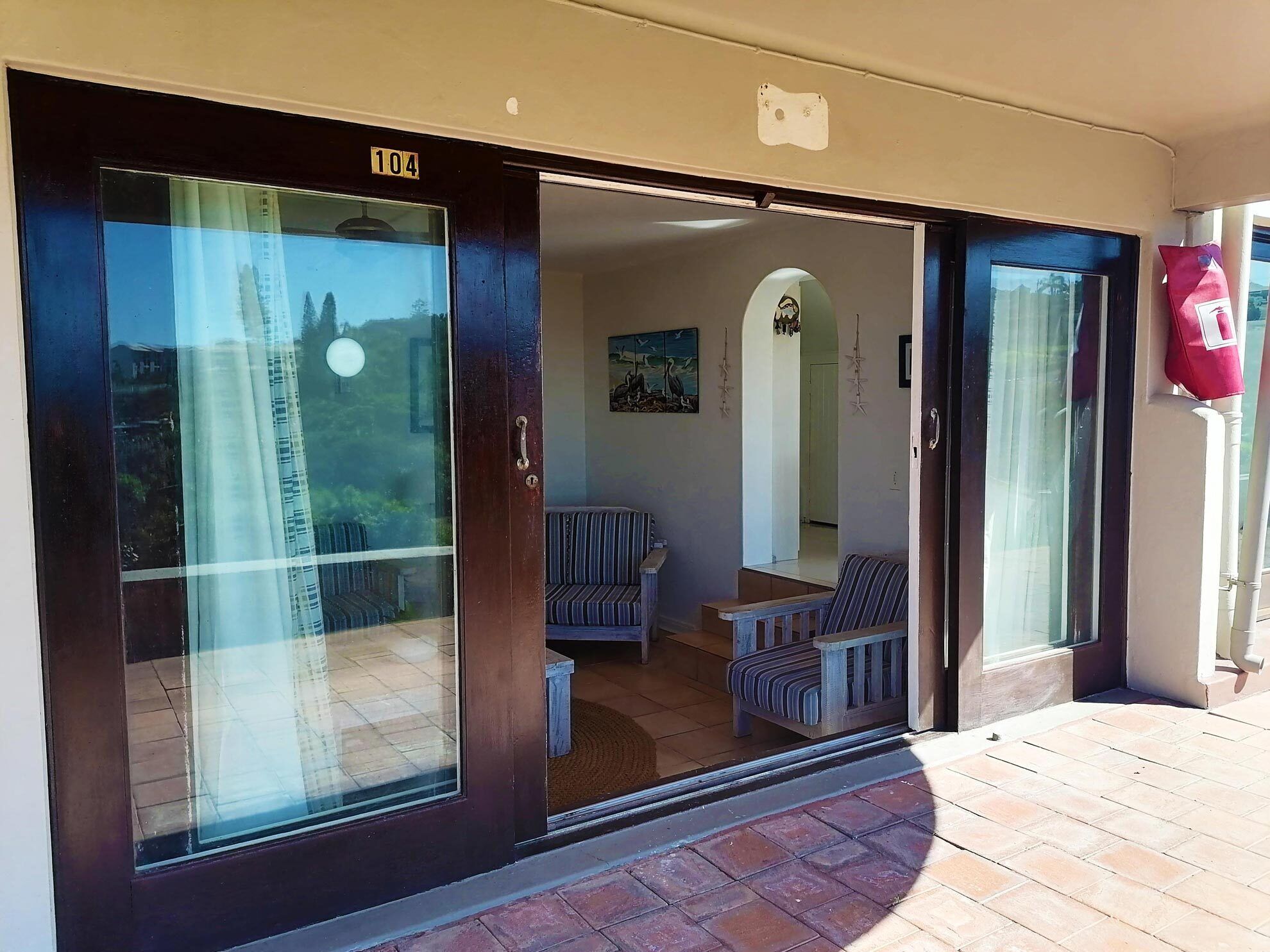 A sliding glass door entrance to a room with a view of a building and a painting on the wall.