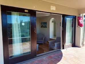 Puerta corrediza de vidrio que da acceso a una habitación con vistas a un edificio y un cuadro en la pared.